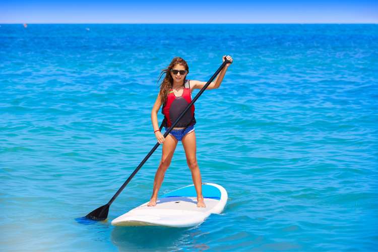 Mädchen-beim-Stand-Up-Paddeln-in-einer-natürlichen-Landschaft-von-Menorca
